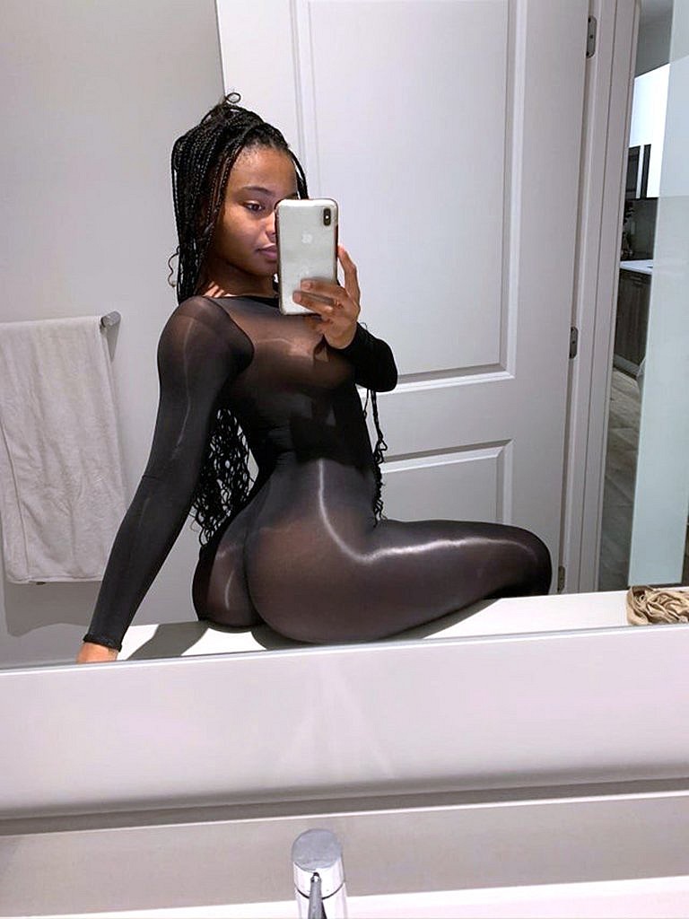Busty black girl encased in black glossy bodystockings